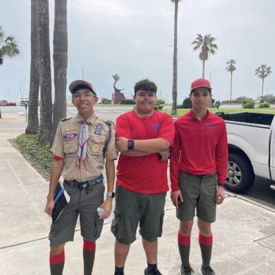three boy scouts pose by palm trees