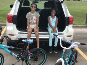 two girls sitting in the back of a truck with bikes