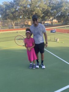 a dad and daughter play tennis
