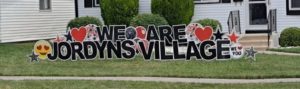 Decorative sign in front yard says "We Are Jordyn's Village"