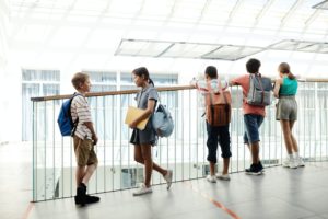 five teens stand in a school hallways talking