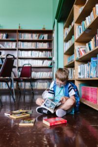 Boy with backpack reads books in the library