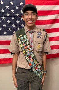 Boy scout poses by American flag