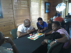 a family of four sits around a table playing a board game